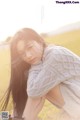 A woman laying on the ground in a field.