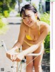 A woman in a yellow bikini riding a bike.