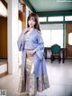 A woman in a blue kimono standing in a room.