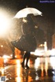 A woman walking in the rain holding an umbrella.